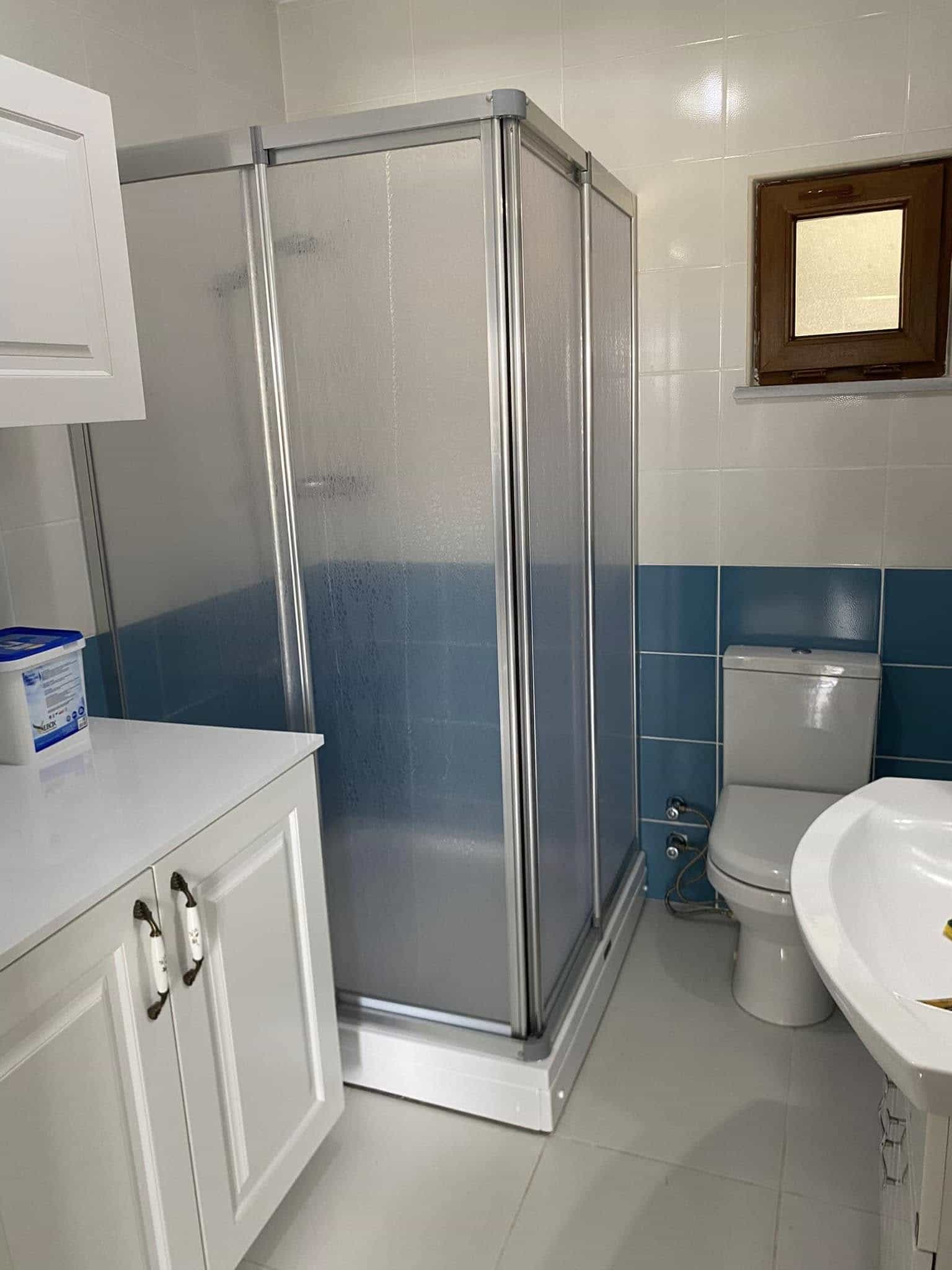 Mavi fayanslı banyo ve cam duş alanı