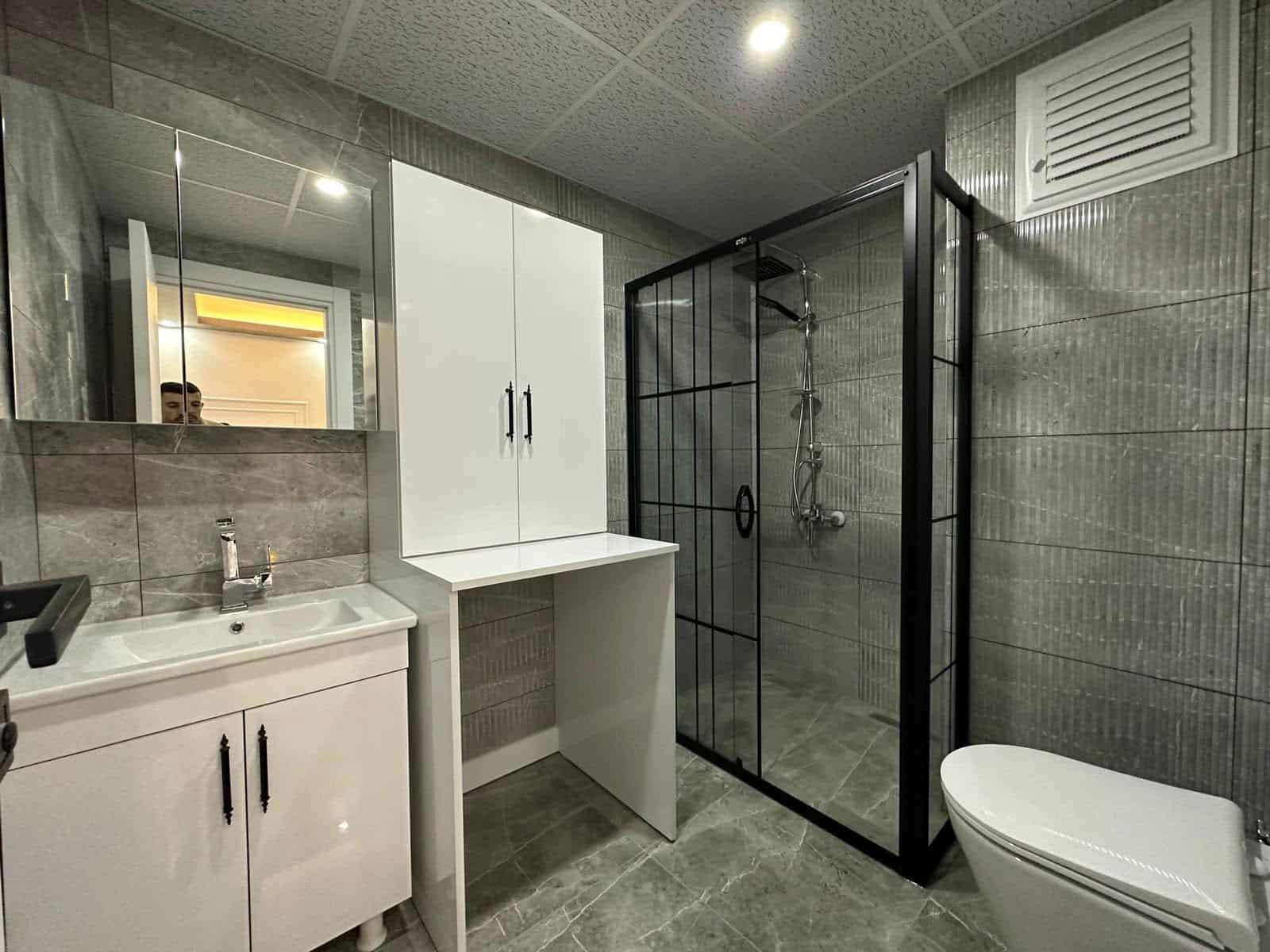 Duş kabini ve geniş lavabo dolabı bulunan banyo